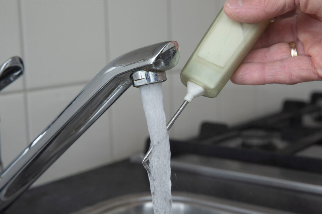 a hand using a thermometer to check the temperature of tap water