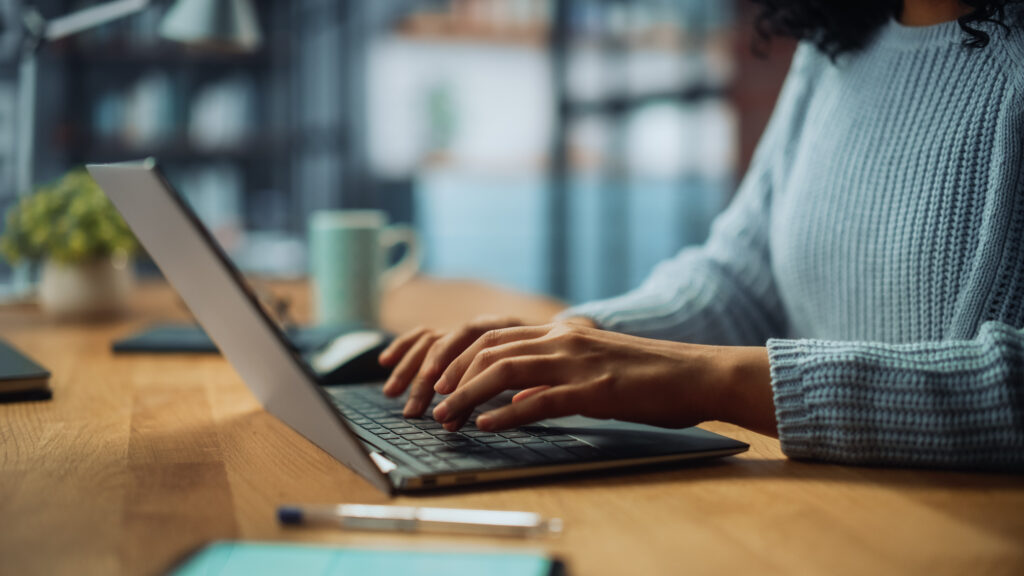 a person working on a laptop at a long wooden table